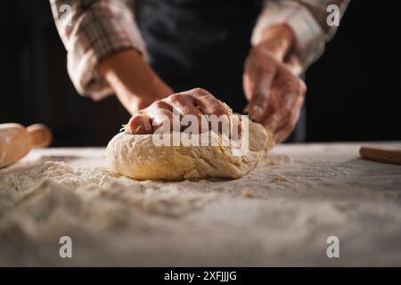 Baking concept. unrecognizable female prepares pastry, kneads dough on wooden table. Woman cook bakes bread Stock Photo