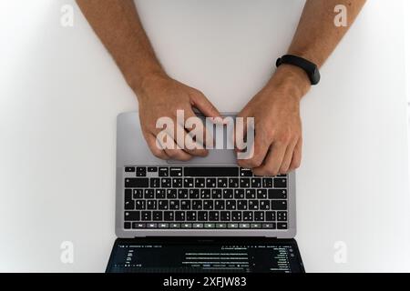 Image of a man's hands with a watch typing on a laptop keyboard Stock Photo