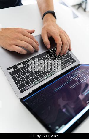 Programmer typing on a laptop, side view Stock Photo