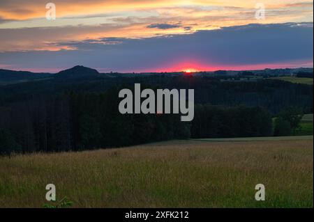 Sunset over rolling hills and fields in a tranquil countryside setting Stock Photo