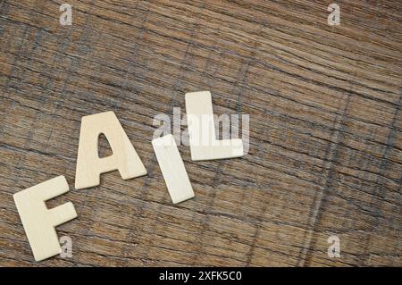 Jumbled letters spelling out FAIL on a woodgrained background Stock Photo