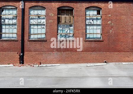 Abandoned brick industrial building with broken and weather worn windows Stock Photo