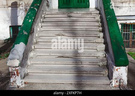 Entrance stairs of abandoned building. The staircase are green and white. The steps are old and worn Stock Photo