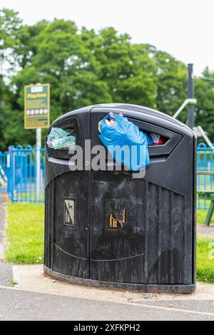 Overflowing rubbish bin in a children s playground Stock Photo Alamy