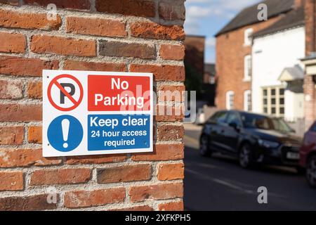 Close up of outdoor sign advising the public: 'No Parking, Keep Clear, 24 hour access required' in street of UK residential area. Stock Photo