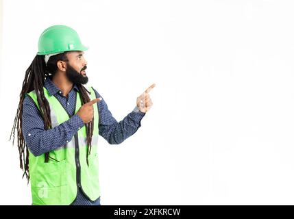 Afro latino engineer man wearing green helmet and green coat over isolated white background happy face smiling pointing to the left. Positive person Stock Photo