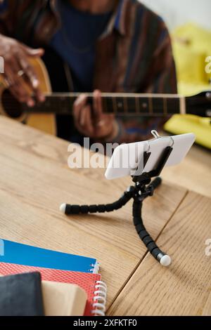 A man serenading with guitar, cell phone on table. Stock Photo