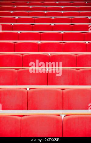 An empty auditorium or lecture hall, showcasing rows of red seats. The seats are empty, creating a sense of anticipation or expectation. Stock Photo