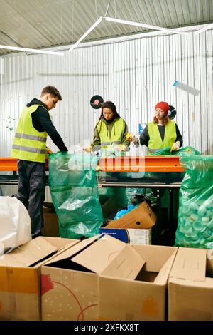 Young volunteers in gloves and safety vests work together to sort through boxes of trash at a table filled with recycling items. Stock Photo