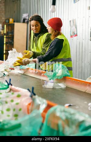 Two young volunteers in gloves and safety vests sorting trash, standing together. Stock Photo
