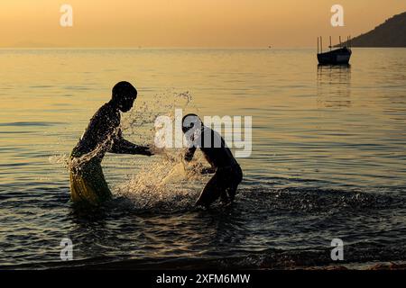 Boy and girl playing in Lake Malawi at sunset, Cape Maclear, Malawi. June 2011 Stock Photo