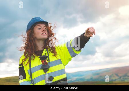 Female site engineer surveyor working with theodolite total station EDM equipment on a building construction site outdoors Stock Photo