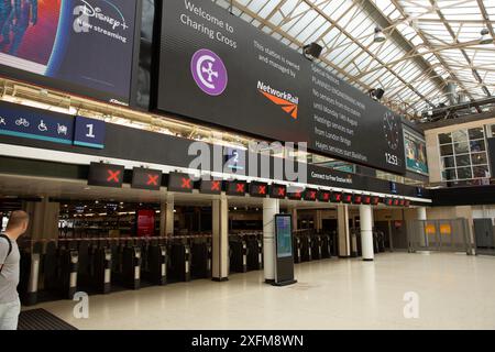 An electric board displays information about planned engineering work for the weekend as gates are seen closed at Charing Cross station in London. Stock Photo