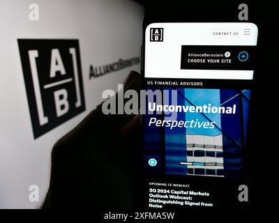 Mobile phone with website of US investment company AllianceBernstein Holding L.P. (AB) in front of logo. Focus on center of phone display. Stock Photo