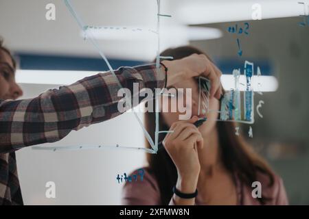 Business team collaboratively brainstorming with sticky notes on a glass wall in a modern office setting Stock Photo
