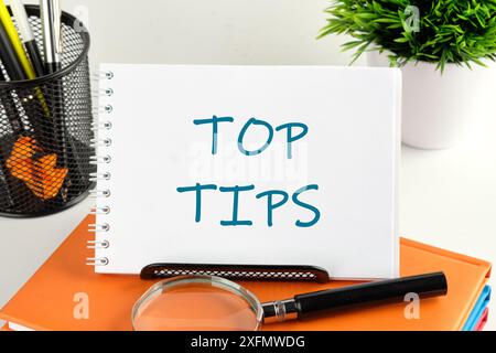 top tips word. text concept symbol TOP TIPS in a small notebook on a business book Stock Photo