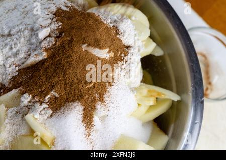 Creating Apple Pie Filling:  Adding cinnamon to the bowl of apples, sugar, flour and nutmeg. Stock Photo