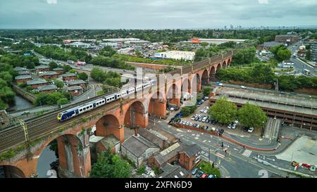 Stockport viaduct with a Northern local commuter train passing over and Manchester skyline on the horizon Stock Photo