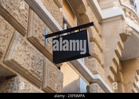 Black rectangular shop sign on a black city facade. Sleek and modern design, perfect for urban branding and storefront advertising Stock Photo