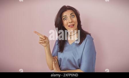 Surprised middle-aged hispanic woman pointing isolated against a pink background Stock Photo