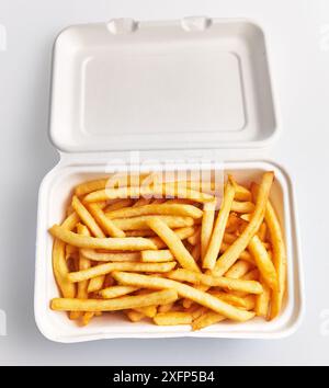 Top view of golden french fries served in a white styrofoam container, isolated on a white background. Stock Photo