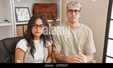 A professional man and woman team sitting together in a modern office, embodying collaboration and partnership. Stock Photo
