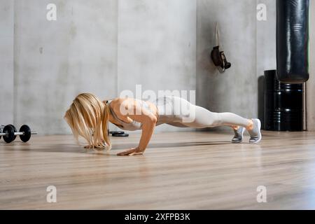 Low angle side view of a fitness woman doing push-ups in the gym Stock Photo