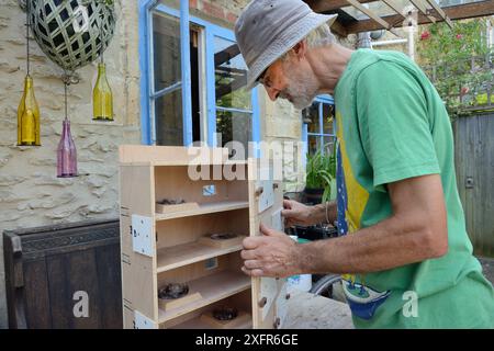 Roger Beckett building a nestbox for Common swifts (Apus apus) with nest cups, access ports for nest inspection and CCTV cameras, to be fitted in a church tower, Hilperton, Wiltshire, UK, June. Model released. Stock Photo