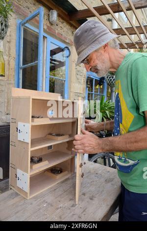 Roger Beckett building a nestbox for Common swifts (Apus apus) with nest cups, access ports for nest inspection and CCTV cameras, to be fitted in a church tower, Hilperton, Wiltshire, UK, June. Model released. Stock Photo
