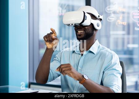 Using VR headset, man interacting with virtual environment in modern office Stock Photo