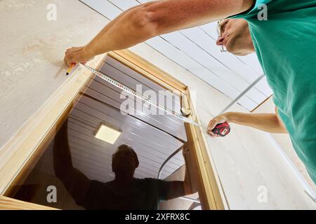 Measuring doorway to mark using tape measure holding piece in place and marking where it needs to be cut with pencil. Stock Photo