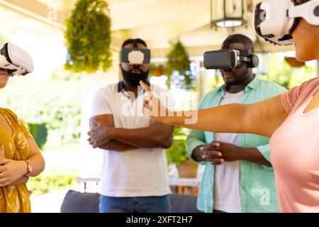 Using VR headsets, group of diverse friends exploring virtual reality together indoors Stock Photo