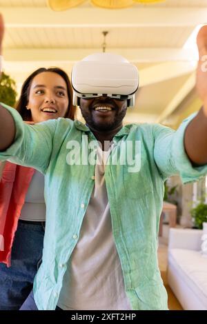 Using VR headset, man exploring virtual reality with friend at home Stock Photo