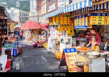 Busan, South Korea - October 7, 2017: Korean woman cooking at street cafe in Jagalchi Fish Market. Traditional street food. Stock Photo