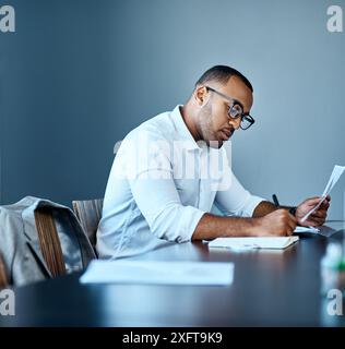Businessman, accountant and writing with documents for finance, report or company budget at office. Young man or employee taking notes with paperwork Stock Photo