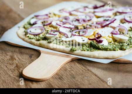 Rucola and basil pesto pizza with mushrooms and vegan cheese before being baked. Stock Photo