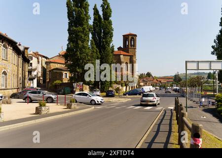 Langeac, France - May 27, 2023: A view of Langeac, France, showing a charming town square with a church in the background, cars driving through, and a Stock Photo