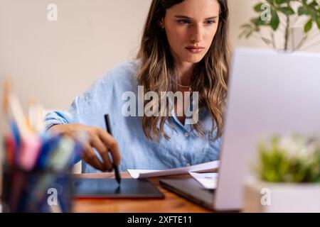 A professional woman working in a home office using a digital tablet. Concentrated and focused - remote work, digital tools, modern technology, creati Stock Photo
