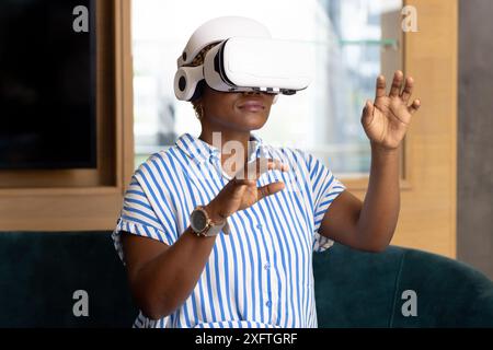 Using VR headset, african american woman in striped shirt experiencing virtual reality simulation Stock Photo