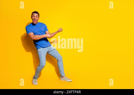 Full length photo of handsome young guy pull empty space dressed stylish blue garment isolated on yellow color background Stock Photo