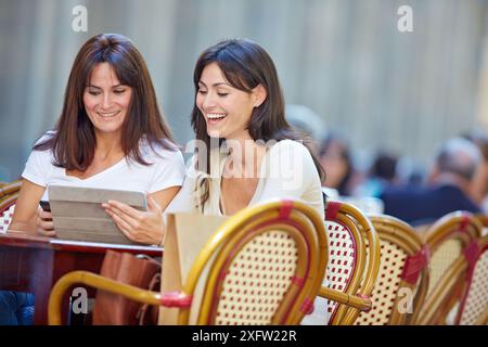 Looking a tablet. Women sisters 35 and 40 years taking coffee on a terrace. Donostia. San Sebastian. Gipuzkoa. Basque Country- Spain. Stock Photo