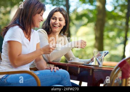 Looking a tablet. Women sisters 35 and 40 years taking coffee on a terrace. Donostia. San Sebastian. Gipuzkoa. Basque Country- Spain. Stock Photo