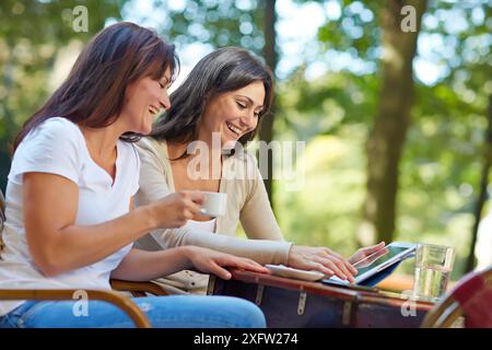 Looking a tablet. Women sisters 35 and 40 years taking coffee on a terrace. Donostia. San Sebastian. Gipuzkoa. Basque Country- Spain. Stock Photo