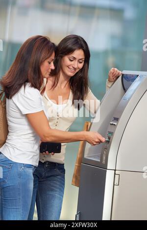 Women sisters 35 and 40 years with credit card at ATM. Shopping on the street. Donostia. San Sebastian. Gipuzkoa. Basque Country- Spain. Stock Photo