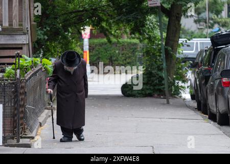 An older unidentifiable Hasidic Jewish man walks slowly to synagogue in Brooklyn, New York. Stock Photo