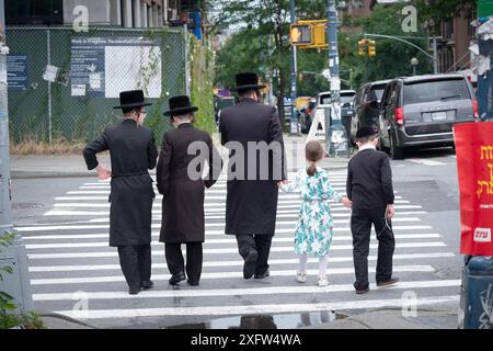 A view from behind of a Hasidic father & 4 children walking south on Lee Avenue in Williamsburg, Brooklyn, New York. Stock Photo