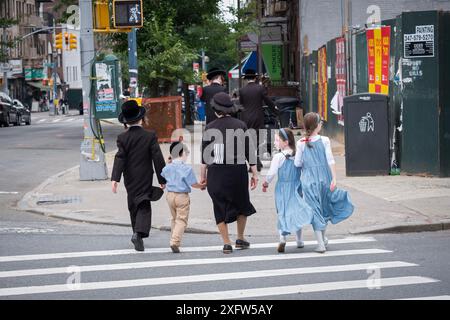 LEE AVE STREET SCENE What appears to be a mother & 4 children walk south on Lee Avenue in Williamsburg on a summer 2024 Sunday. Stock Photo