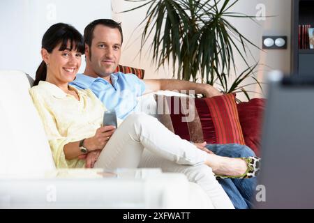 Couple sitting on coach watching TV in the living room Stock Photo