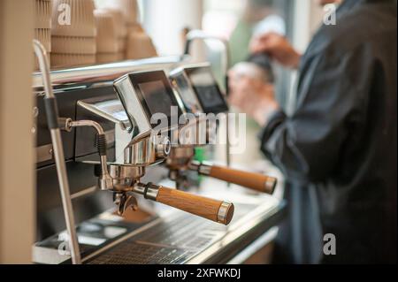 Modern coffee machine in a minimalist-style coffee shop. A man's hand is shown preparing coffee. Selective focus. Stock Photo