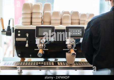 Modern coffee machine in a minimalist-style coffee shop. A man's hand is shown preparing coffee. Selective focus. Stock Photo